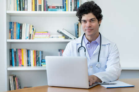 Portrait of caucasian doctor or scientist at computer at office at clinicの写真素材
