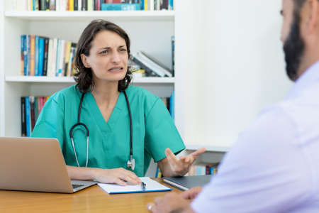 Caucasian female doctor talking with patient at office at hospitalの写真素材
