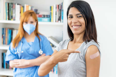 Laughing latin american woman after third vaccination against Covid 19 with nurse vaccination centerの写真素材