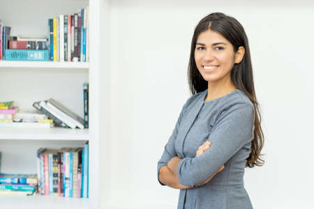 Pretty hispanic businesswoman with crossed arms at officeの写真素材