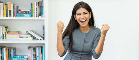 Laughing and cheering hispanic businesswoman at officeの写真素材