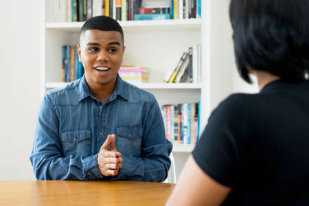 Thankful hispanic trainee talking at job interview at officeの写真素材