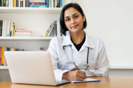 Beautiful latin american mature doctor at work at work at office at hospitalの写真素材