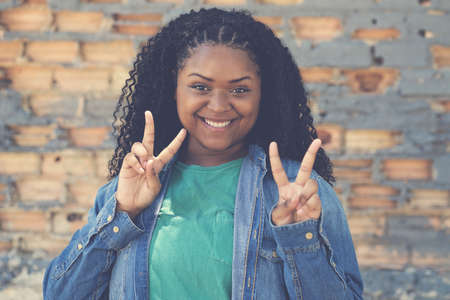 African american female young adult showing victory gesture outdoor in urban city styleの写真素材