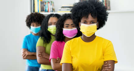 Group of african american female young adults with colorful face masks   recommending protection against Covid-19 virusの写真素材