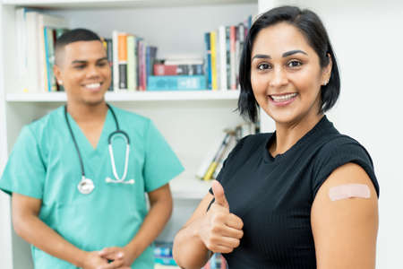 Pretty hispanic mature woman with nurse after vaccination at hospitalの写真素材