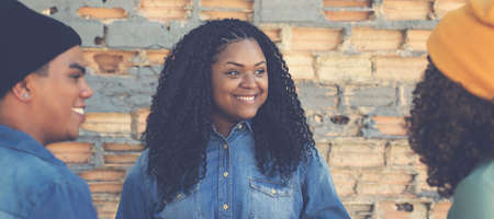 Pretty african american female young adult talking with hispanic friends outdoor in urban city styleの写真素材