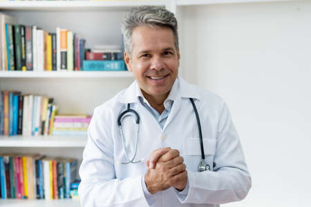 Handsome senior doctor with gray hair at office of hospitalの写真素材
