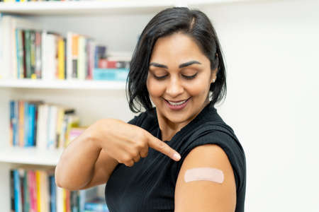 Laughing latin american mature woman with plaster after vaccination at hospitalの写真素材