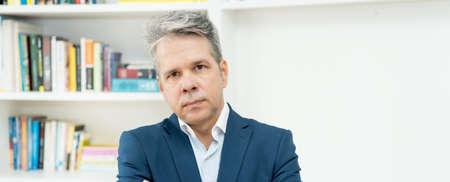 Serious mature businessman with competence and self-confidence at office of companyの写真素材