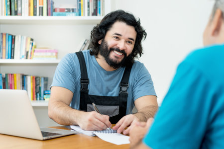 Laughing handyman talking about contract and order with customer at workplaceの写真素材