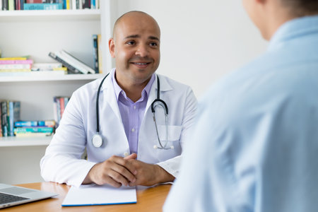 Friendly bald head doctor talking with patient at office of clinicの写真素材