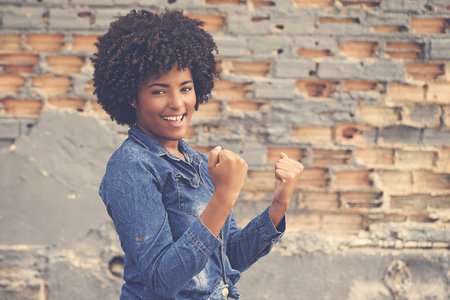 Successful cheering african american young adult woman outdoor in cityの写真素材