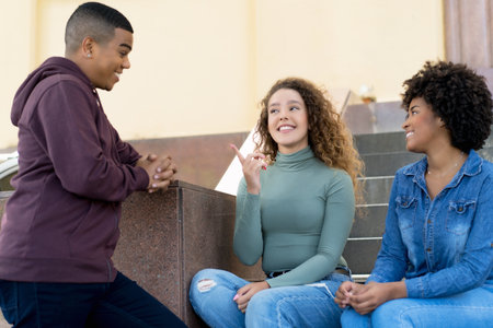 Group of talking hispanic and caucasian and african american young adults outdoor in the cityの写真素材
