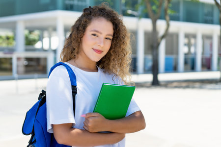 Beautiful german female student with backpack and paperwork outdoor in cityの写真素材