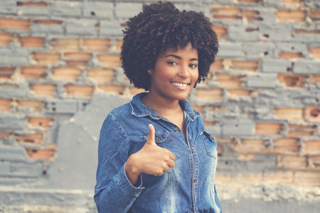African american young adult woman showing thumb up outdoor in cityの写真素材