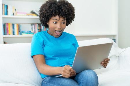 African american young adult woman streaming movie at computer indoors at homeの写真素材