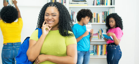 Laughing african american female student with group of college students indoors at libraryの写真素材