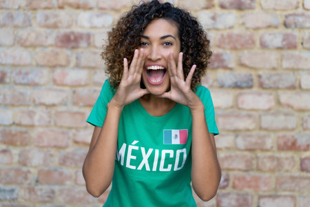 Shouting mexican female football fan with green soccer jerseyの写真素材