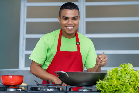Happy latin american chef apprentice  preparing vegetarian or vegan food at kitchen of restaurantの写真素材