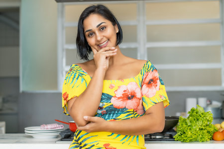Beautiful hispanic mother or housewife at kitchen indoors at homeの写真素材