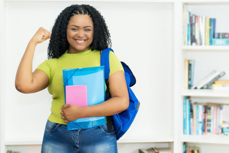 Successful black female student with backpack and paperwork at classroom of collegeの写真素材