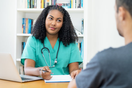 Beautiful latin american female nurse or young doctor listening to patient at office of hospitalの写真素材