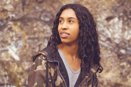 Dreaming mexican female young adult in camouflage clothing outdoor in urban city styleの写真素材