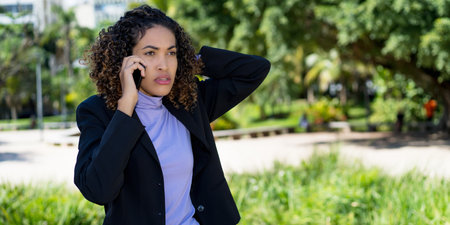 Shocked mexican businesswoman at phone outdoor in cityの写真素材