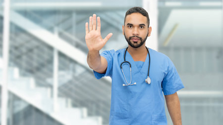 Mexican male nurse or doctor with beard and stethoscope gesturing stop at clinicの写真素材