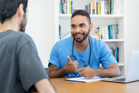 Positive young hispanic doctor or nurse talking with patient at office of hospitalの写真素材