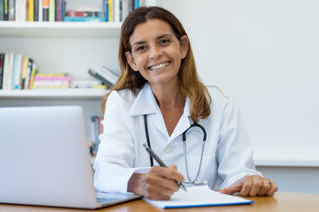 Laughing mature adult female doctor at work at office of hospitalの写真素材