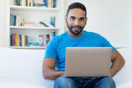 Handsome latin american male programmer at work at computer indoors at home officeの写真素材