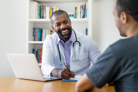 Laughing mature adult african american male doctor listening to patient at office of hospitalの写真素材