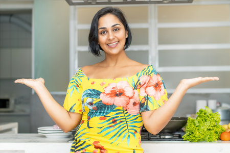 Pretty hispanic mother or housewife at kitchen indoors at homeの写真素材