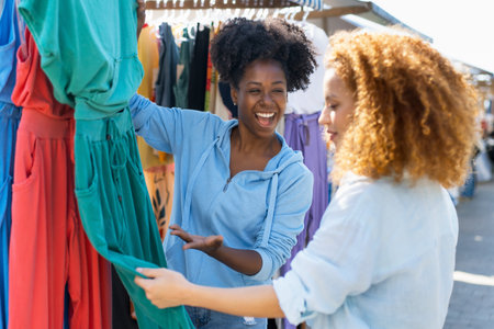 African american woman talking with client at flea market outdoor in city in summerの写真素材