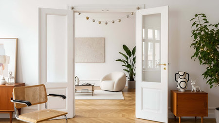 Open double doors showing open white double doors leading to a living room with beige armchair and...