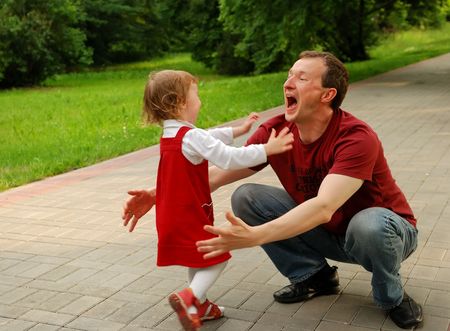 Father playing with the daughter. Man waiting to embrace her while little girl throwing herself into his armsの写真素材