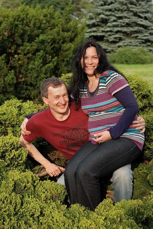 Young happy smiling couple (man and pregnant woman) sitting on the tree outdoor in the summer garden. Look my other photos from this seriesの写真素材