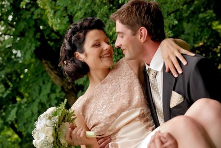 Happy smiling wedding couple outdoors. Man is holding woman with bunch of flowers in his arms. Find other nice peoples photos in my portfolio.の写真素材