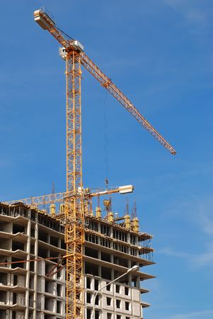 High yellow tower crane building a multistory over blue sky. Lower point of view.の写真素材