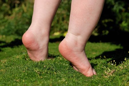 feet of little baby staying on green grassの写真素材
