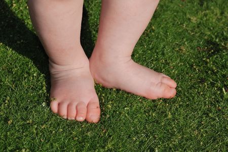 Two feet of little baby staying on green grassの写真素材