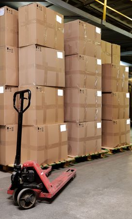 Group of carton boxes and manual fork pallet truck in warehouseの写真素材