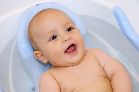 smiling Baby lying in the bath with waterの写真素材