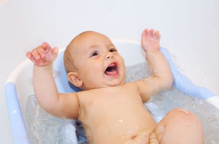 Baby playing and laughing during bathing with waterの写真素材