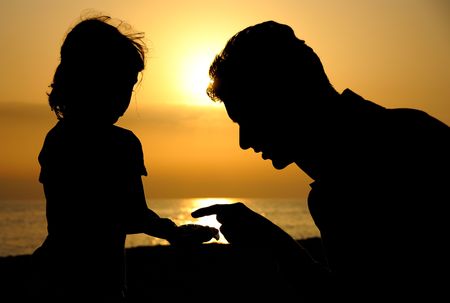 Silhouette of Man and little girl over sunsetの写真素材
