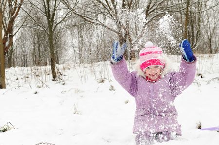 little happy girl playing at snowy winter outdoorの写真素材