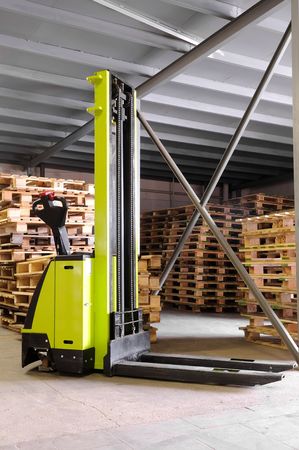 Electric forklift stacker in warehouse in front of cardboard boxesの写真素材