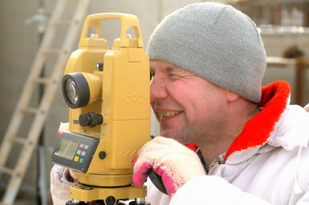 Land surveyor working with theodolite at a construction site